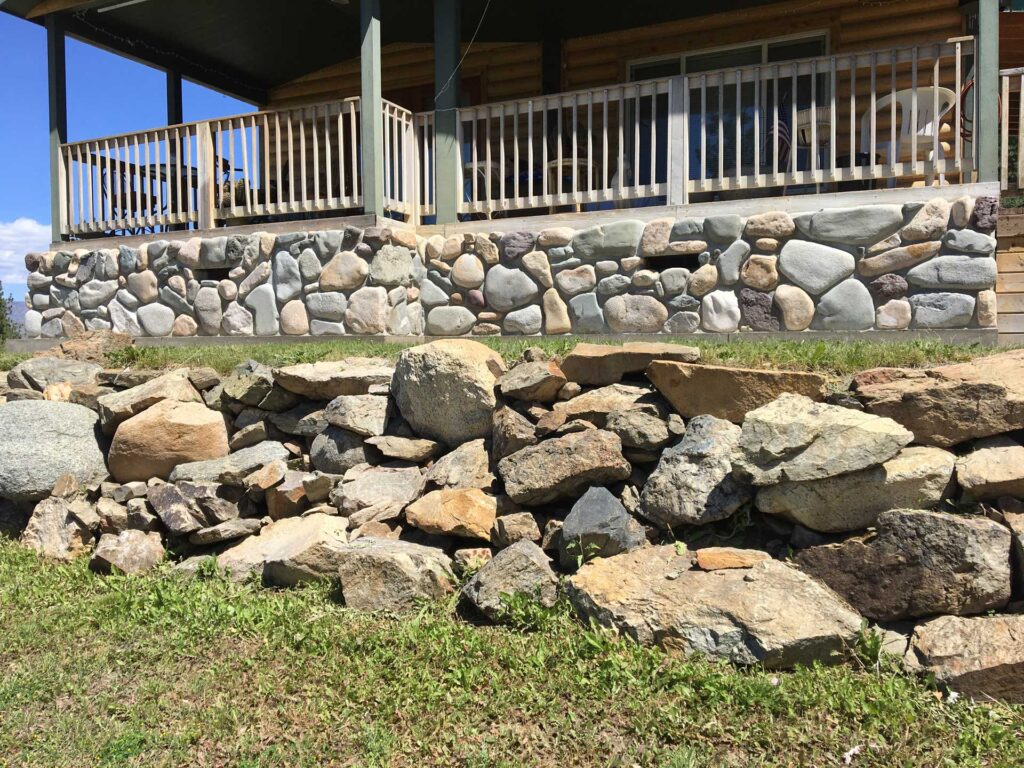 Natural stone wainscoting and veneer on a luxury log home exterior.