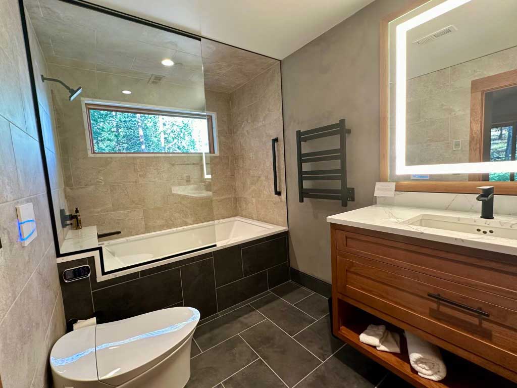 Custom modern bathroom with large-format wall tile, glass shower, and integrated soaking tub.