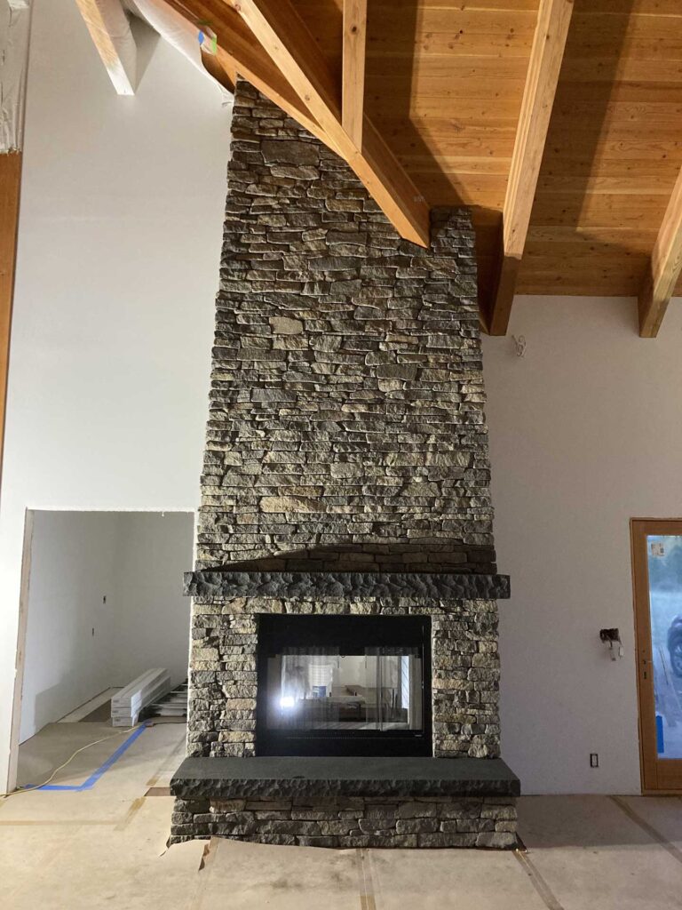 Floor-to-ceiling dry stack stone fireplace with timber mantel in Winthrop, WA.