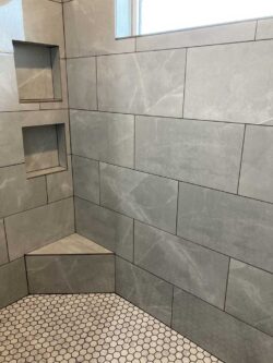 Custom Shower Masonry Custom walk-in shower with large-format gray tile and built-in niches.