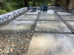 Artisan Outdoor Living Luxury outdoor patio with stone inlays and masonry retaining walls.