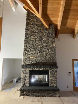 The Modern Hearth Floor-to-ceiling dry stack stone fireplace with timber mantel in Winthrop, WA.