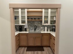 Intricate Mosaic Detail Multicolors gray and white mosaic tile backsplash in a modern kitchen pantry.