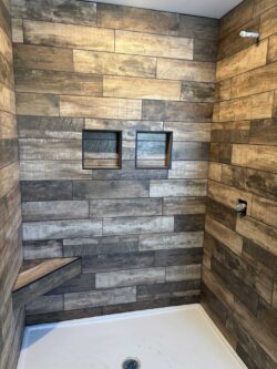 Rustic Artisan Tile Rustic wood-look tile shower with dual integrated niches and custom corner bench.